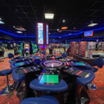 Une table de roulette électronique au centre avec des sièges bleus au casino de Boutersem.