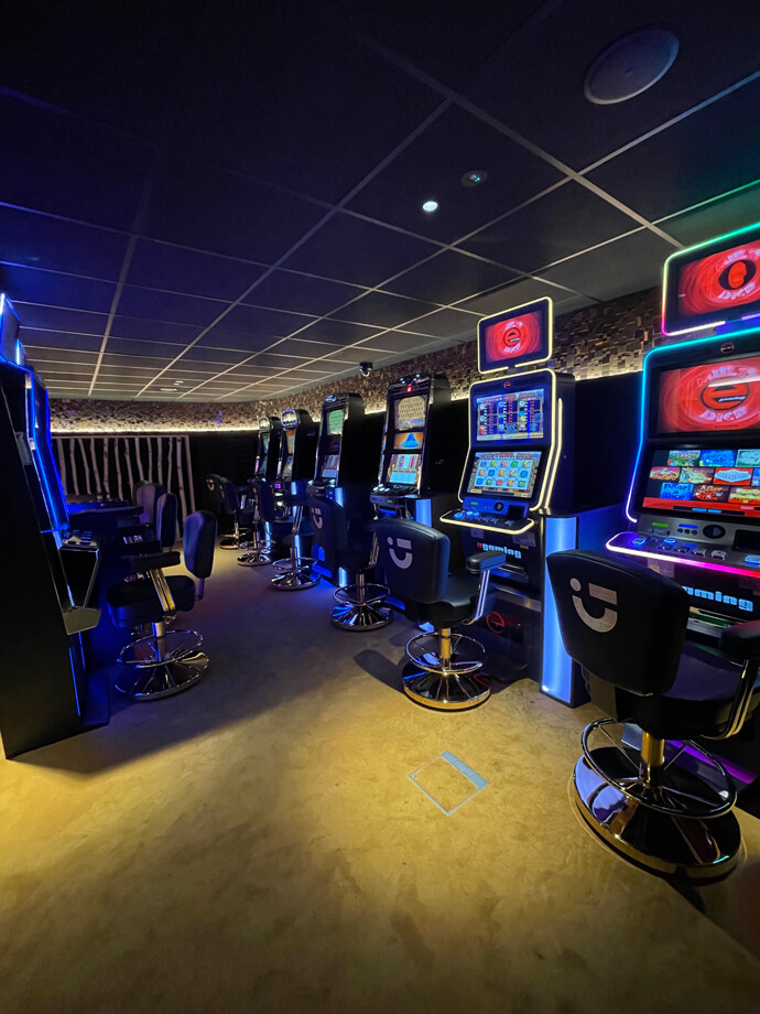 Une rangée de machines à sous modernes avec des sièges noirs au casino de